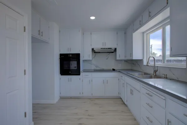 a kitchen with granite countertop white cabinets and stainless steel appliances