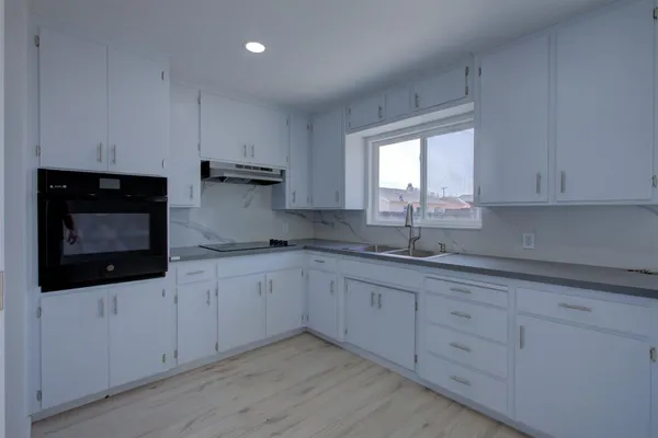 a kitchen with granite countertop white cabinets white stainless steel appliances and sink