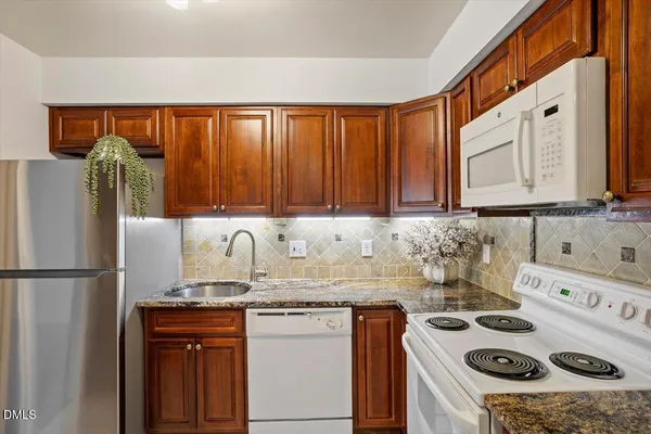a kitchen with granite countertop a sink a stove and a refrigerator