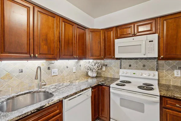 a kitchen with granite countertop a sink stove top oven and cabinets
