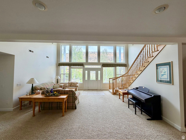 1133 Paris Canyon Road Paris, ID 83261 - Photo 10 of 75 Expansive living space featuring a two-story ceiling, a grand staircase with wood banister, a wall of windows, recessed lighting, and neutral carpeting
