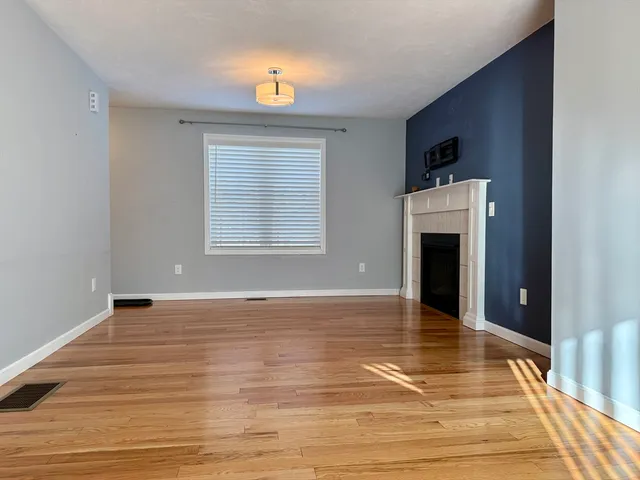 a view of an empty room with window and wooden floor