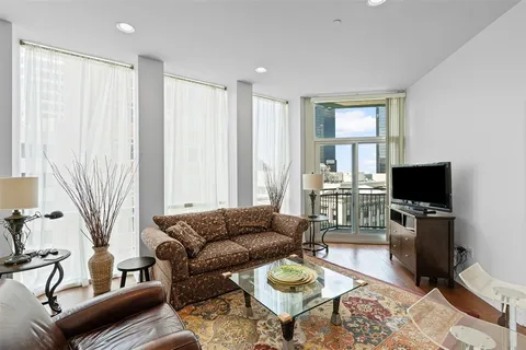a living room with furniture a flat screen tv and a window
