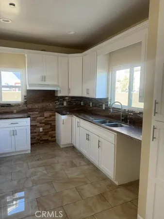 a kitchen with granite countertop a sink a stove and cabinets