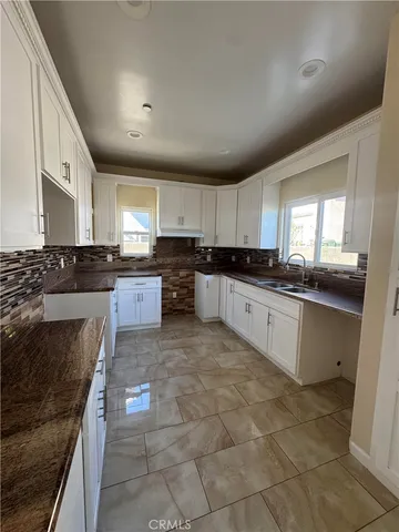 a large kitchen with granite countertop a stove top oven a sink a counter space and cabinets