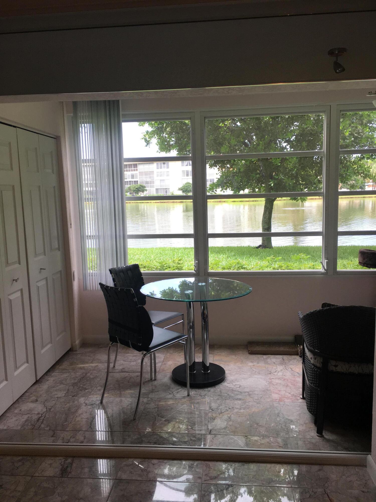 1904 Bermuda Circle, Unit H1 Coconut Creek, FL 33066 - Photo 20 of 72 a living room with a floor to ceiling window and wooden floor