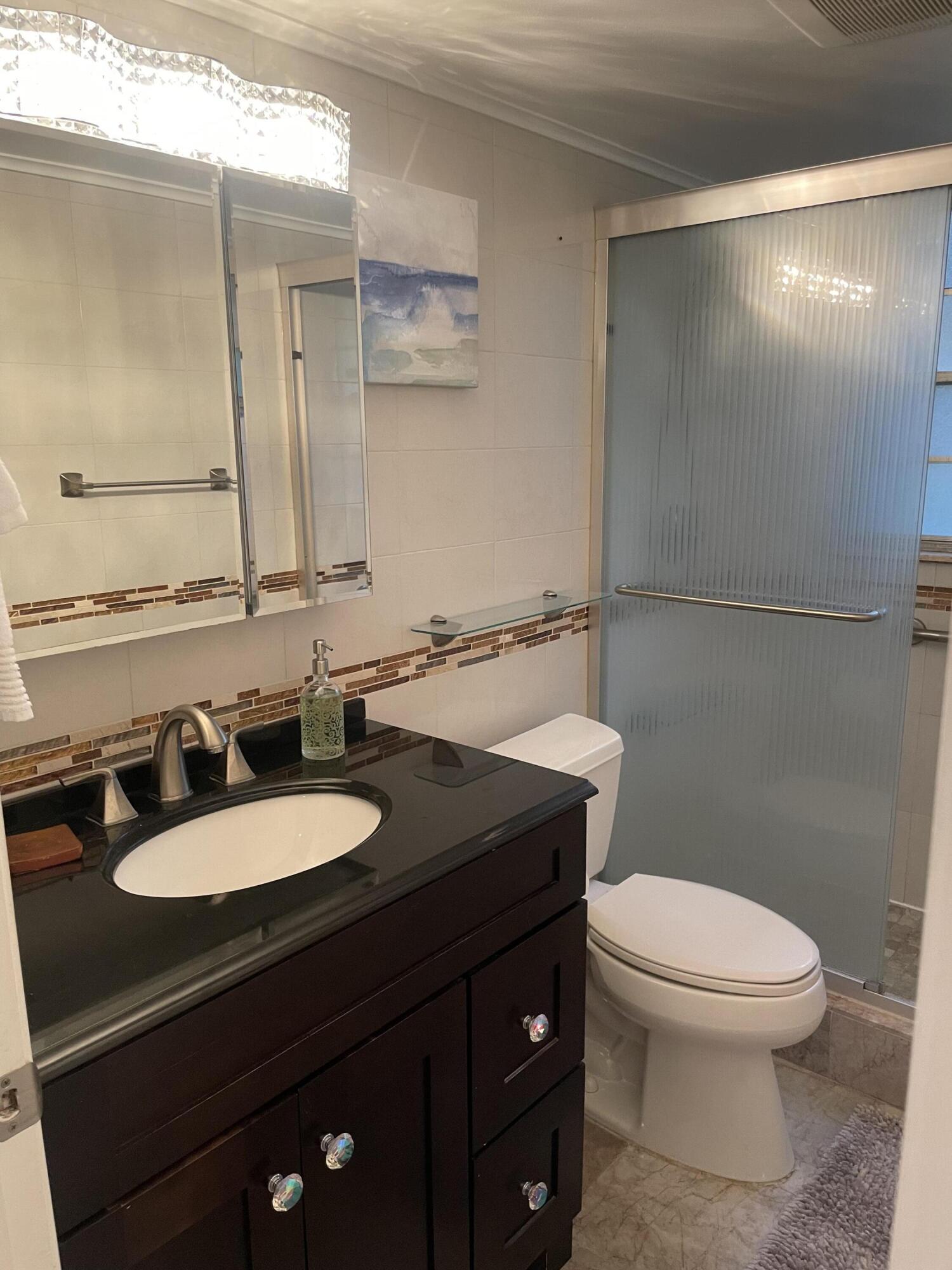 1904 Bermuda Circle, Unit H1 Coconut Creek, FL 33066 - Photo 41 of 72 a bathroom with a granite countertop toilet sink and mirror