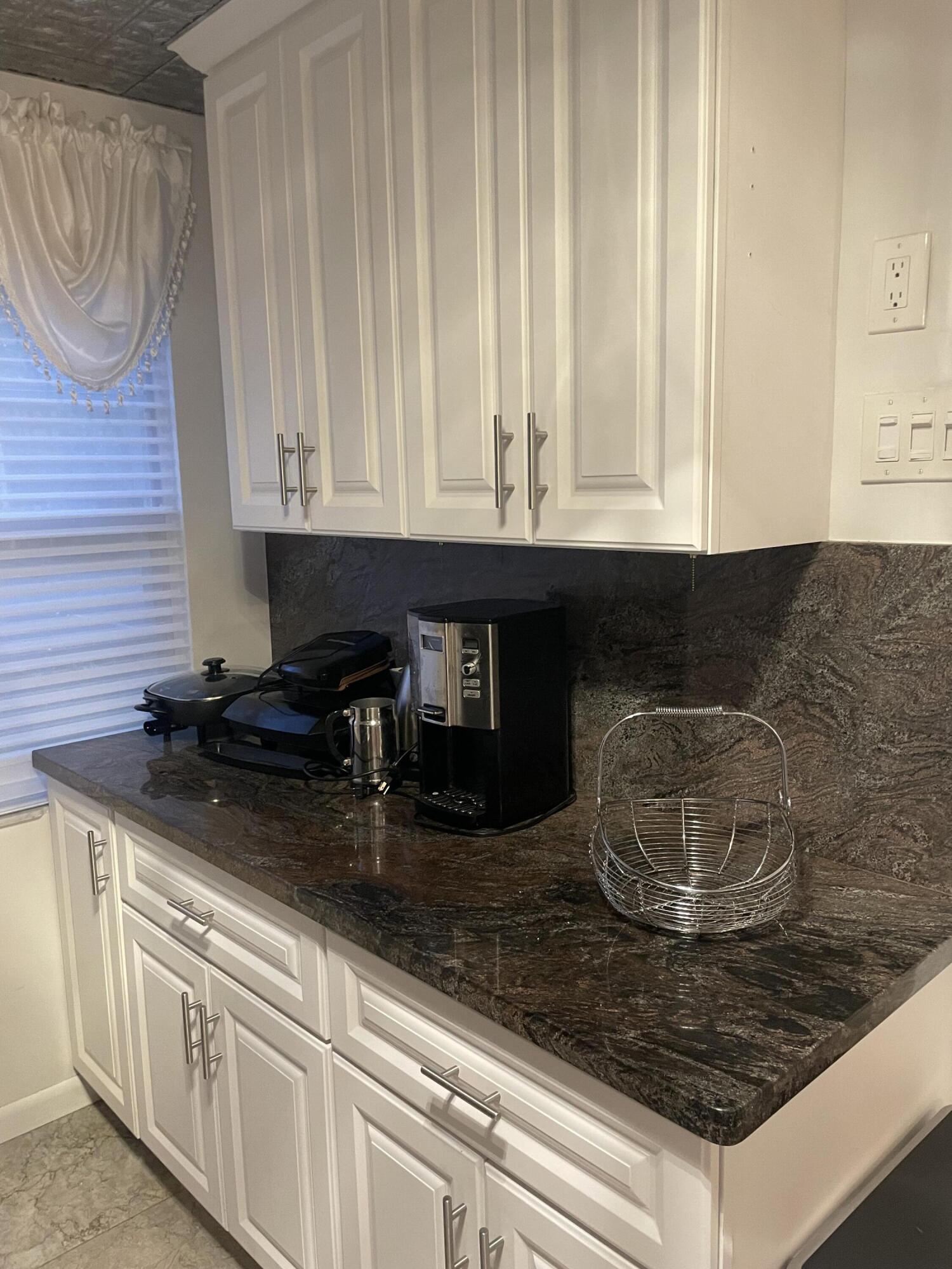 1904 Bermuda Circle, Unit H1 Coconut Creek, FL 33066 - Photo 8 of 72 a kitchen with granite countertop a sink and a white wooden cabinets