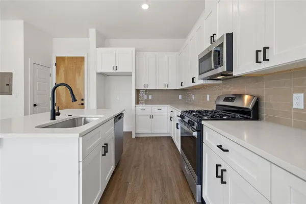 a kitchen with appliances a sink and cabinets