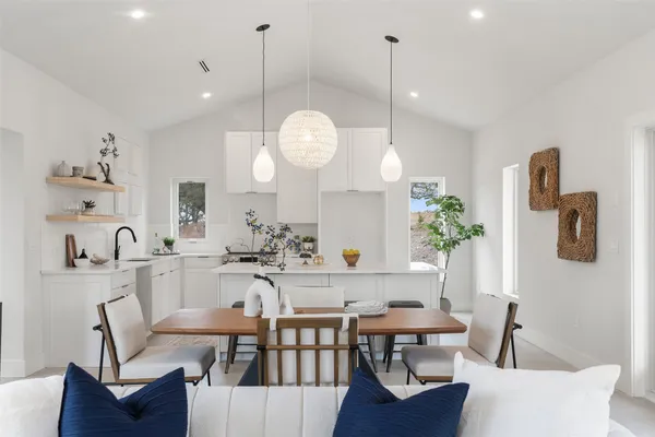 a view of a dining room and livingroom with furniture wooden floor a rug and a chandelier