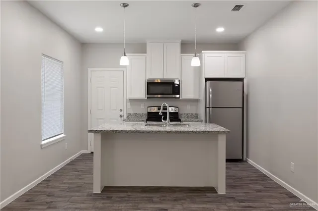 a kitchen with kitchen island a sink wooden floor and a refrigerator