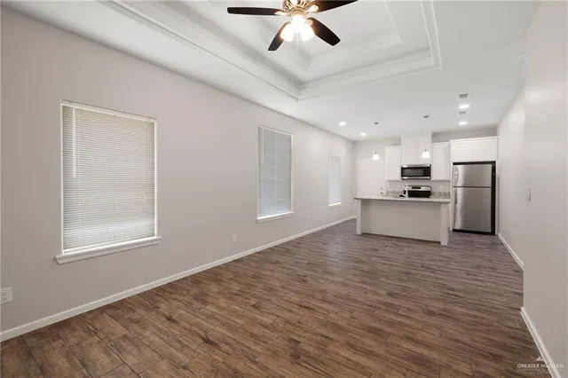 a view of an empty room with window and wooden floor