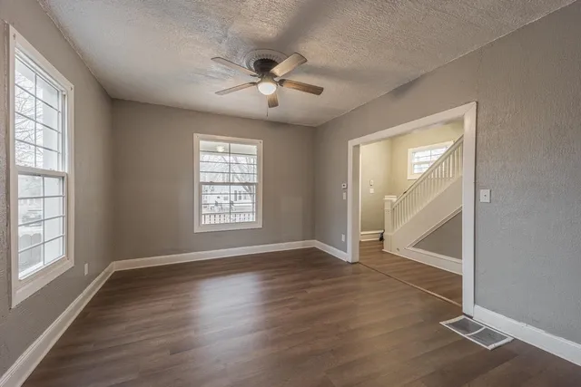 a view of an empty room with wooden floor and a window