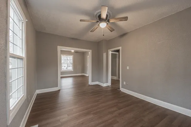 a view of an empty room with wooden floor and a window