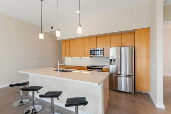 a kitchen with stainless steel appliances a refrigerator a stove a sink and a chairs