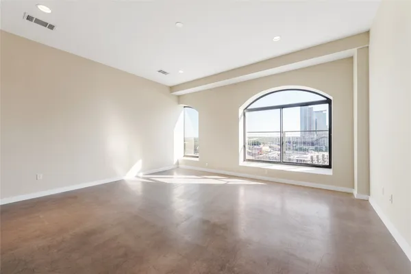 a view of an empty room with a window and wooden floor