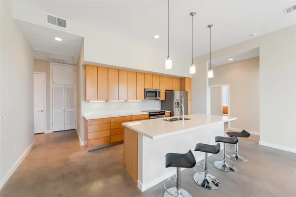 a large kitchen with kitchen island a stove a sink a dining table and chairs with wooden floor