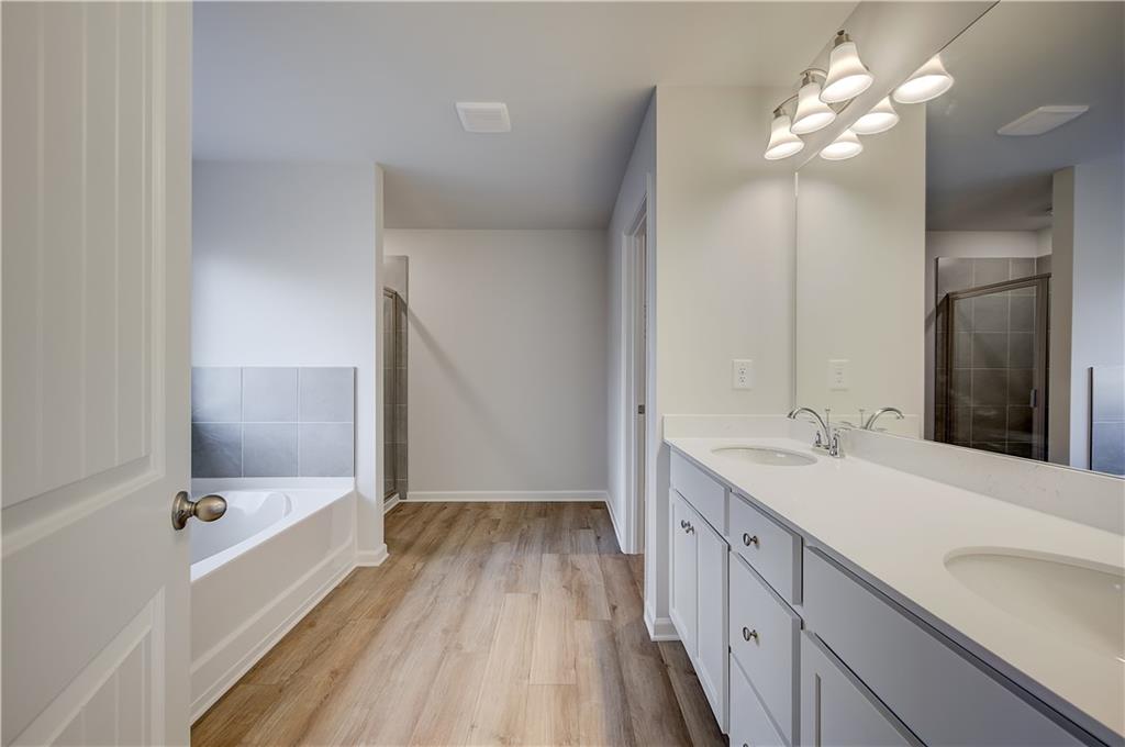 113 St Anne's Place Covington, GA 30016 - Photo 25 of 31 a bathroom with a double vanity sink a large mirror and a bathtub