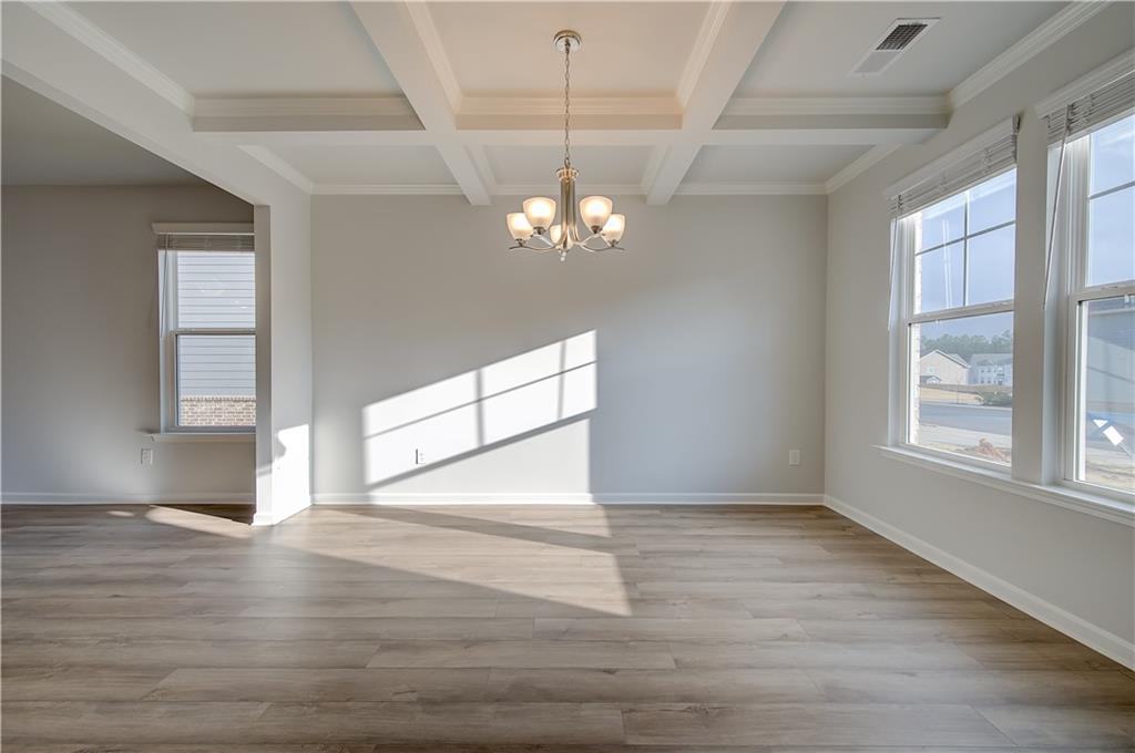 113 St Anne's Place Covington, GA 30016 - Photo 5 of 31 an empty room with wooden floor chandelier and windows