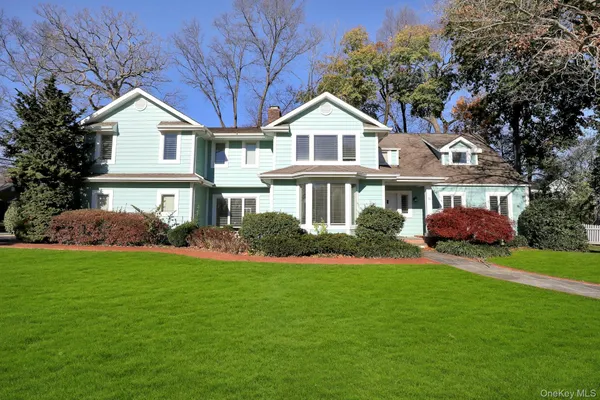 a front view of a house with a garden and trees