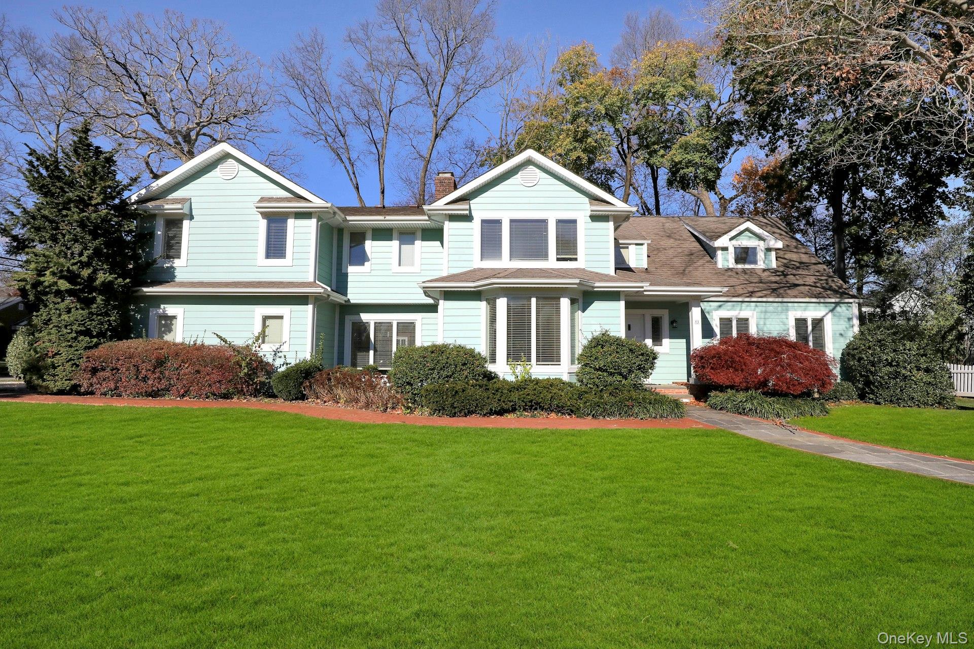 a front view of a house with a garden and trees