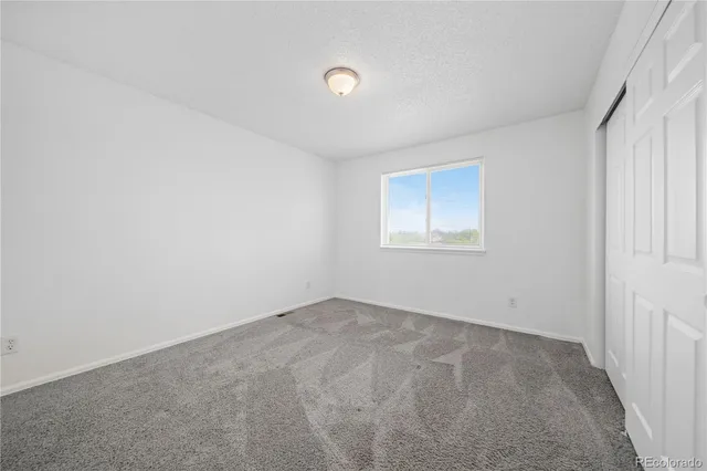 an empty room with ceiling fan and window