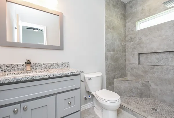 a bathroom with a granite countertop sink a toilet and a mirror