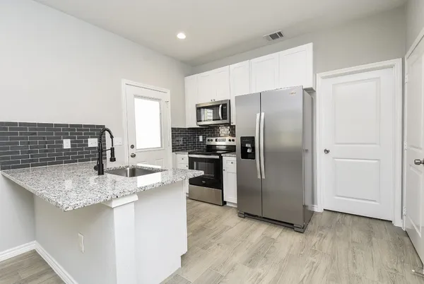 a kitchen with refrigerator a sink and microwave