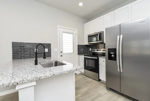 a kitchen with stainless steel appliances white cabinets and a stove top oven