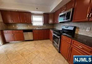 a kitchen with stainless steel appliances granite countertop wooden cabinets a stove top oven a sink and dishwasher