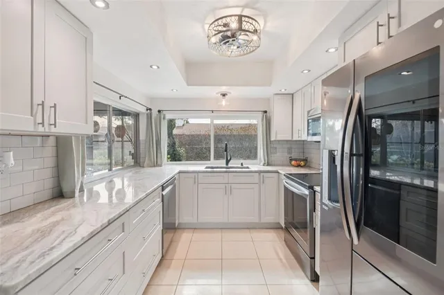 a large kitchen with stainless steel appliances granite countertop a sink and dishwasher a refrigerator