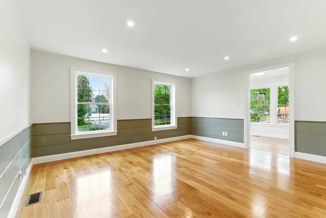 a view of an empty room with a window and wooden floor