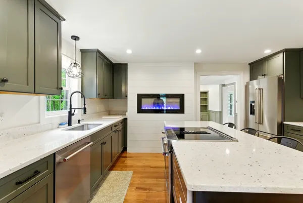 a kitchen with stainless steel appliances granite countertop a sink dishwasher and a refrigerator with wooden floor