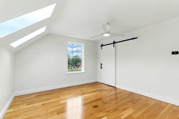 a view of empty room with wooden floor and fan