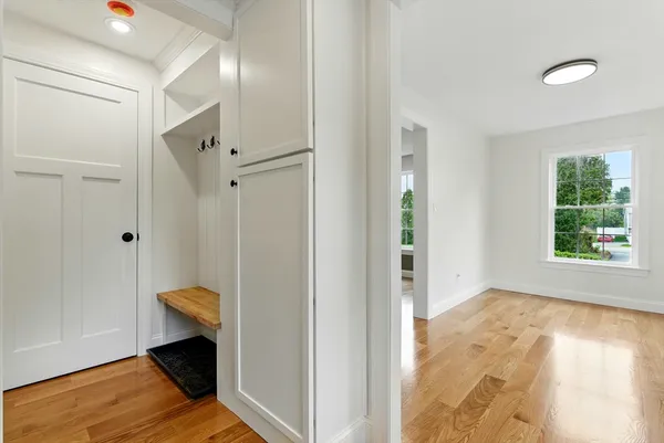 a view of hallway with window and wooden floor