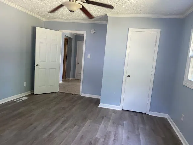 an empty room with wooden floor and a ceiling fan