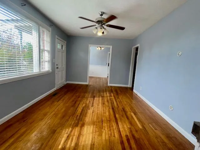 a view of empty room with wooden floor and fan