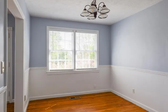 a view of a room with a large window a chandelier fan and wooden floor
