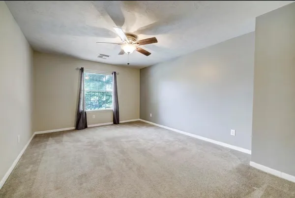 an empty room with windows and fan