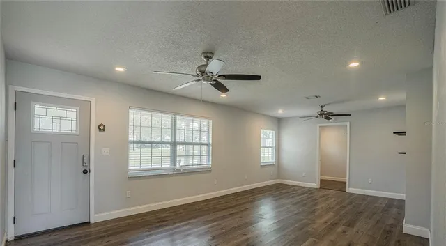 a view of an empty room with wooden floor and a window