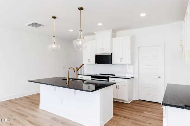 a kitchen with stainless steel appliances granite countertop a sink a microwave oven and a wooden floor