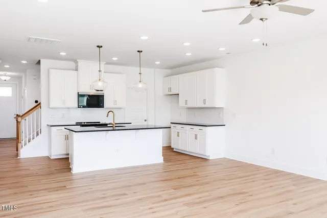 a kitchen with stainless steel appliances kitchen island granite countertop a stove a sink and white cabinets