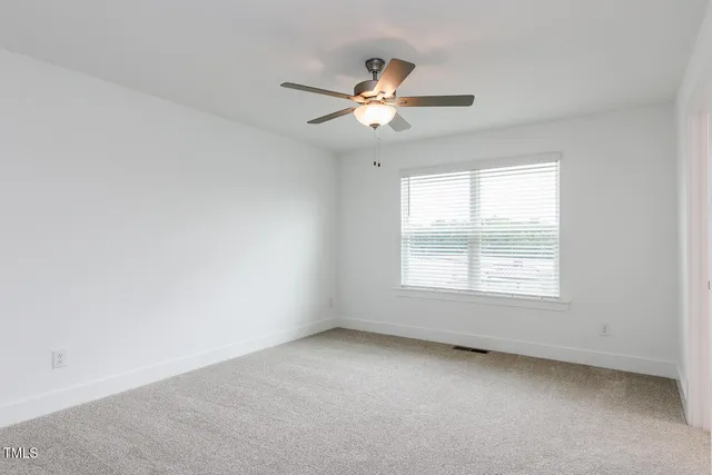 an empty room with a window and a fan