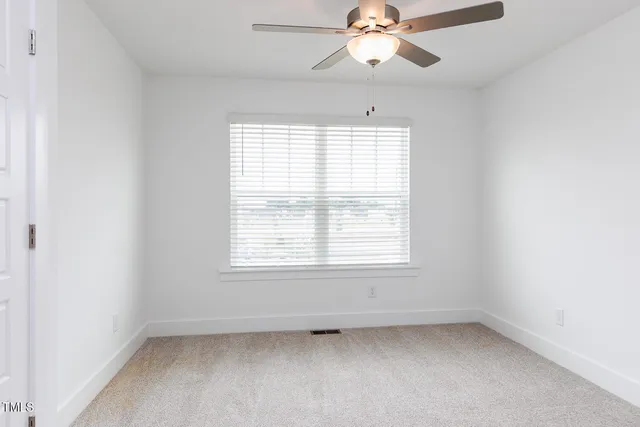 an empty room with a window and a fan
