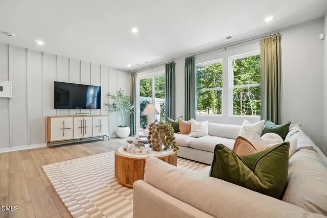 a living room with furniture a flat screen tv and a large window