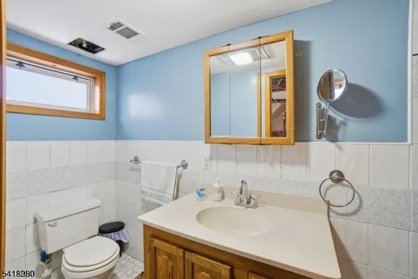 a bathroom with a toilet sink vanity granite and mirror