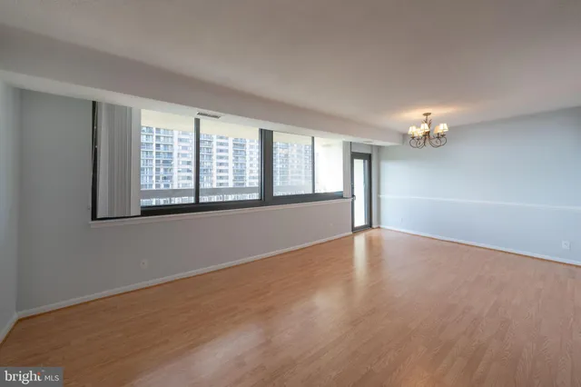a view of an empty room with chandelier and a window