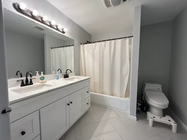 a spacious bathroom with a double vanity sink and a toilet