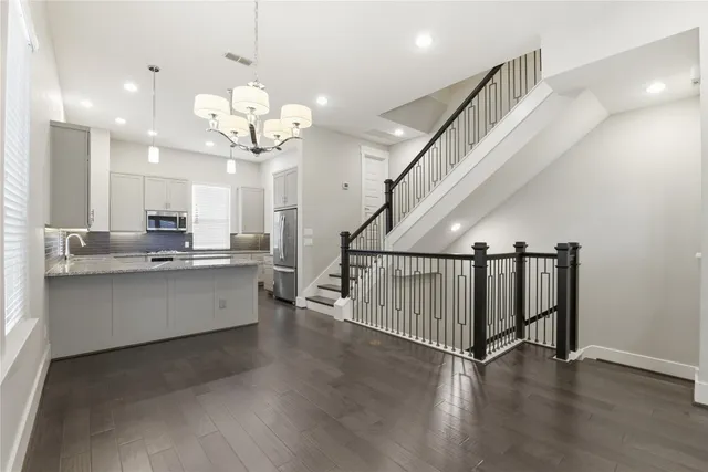 an empty room with wooden floor chandelier fan and windows