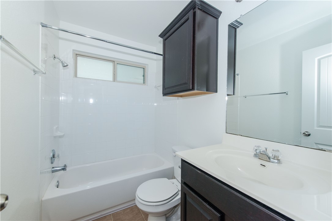 1007 Plateau Trail Georgetown, TX 78626 - Photo 25 of 32 a bathroom with a granite countertop sink toilet a mirror and bathtub